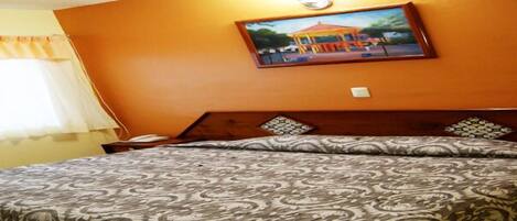 Una habitación de hotel con una cama, una mesita de noche y un cuadro en la pared.