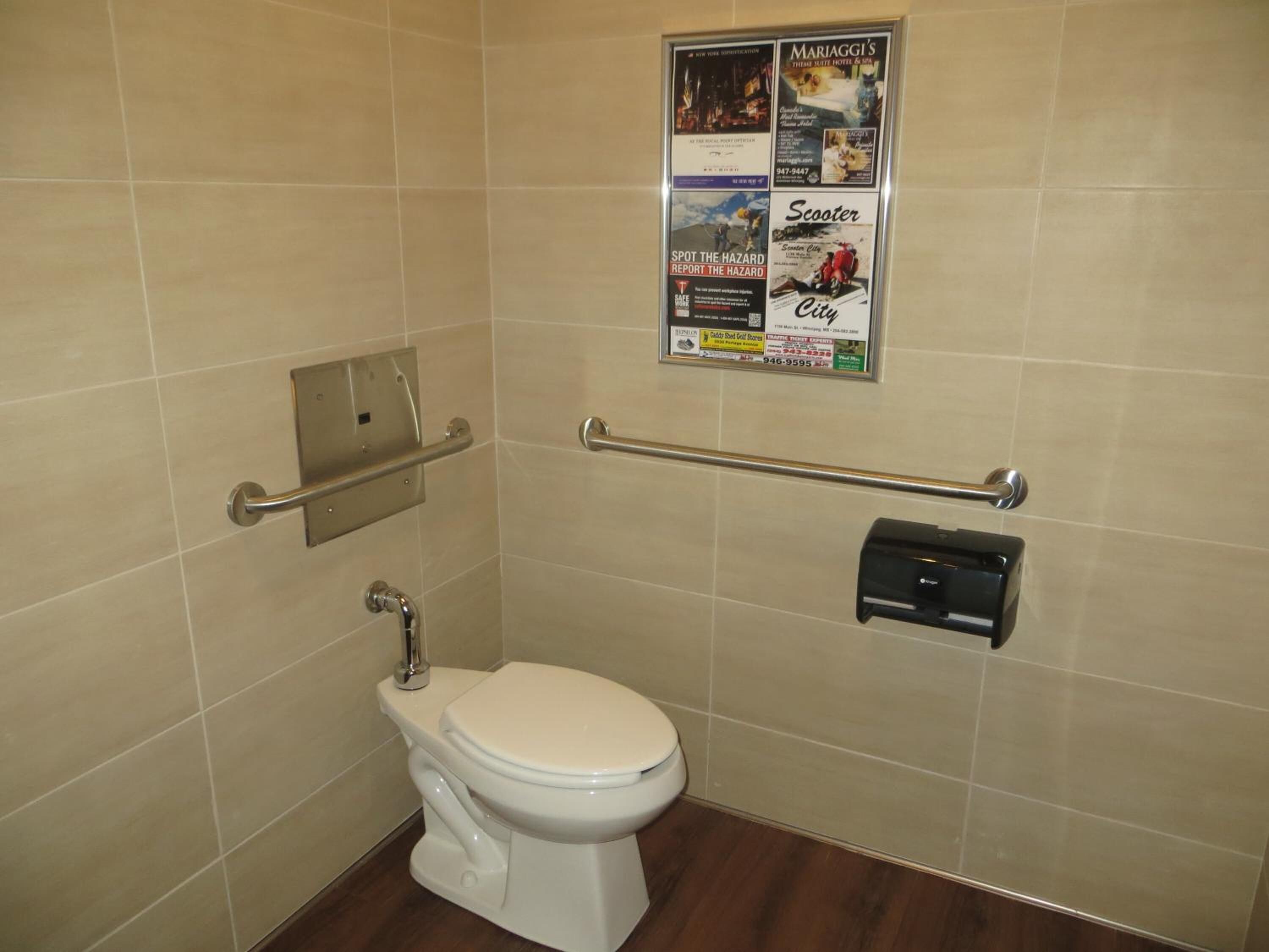 Un baño pequeño y moderno con inodoro blanco, secador de manos y barra de apoyo.