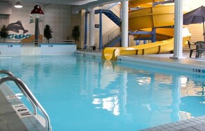 Una piscina interior con tobogán, un mural de delfines y una escalera.