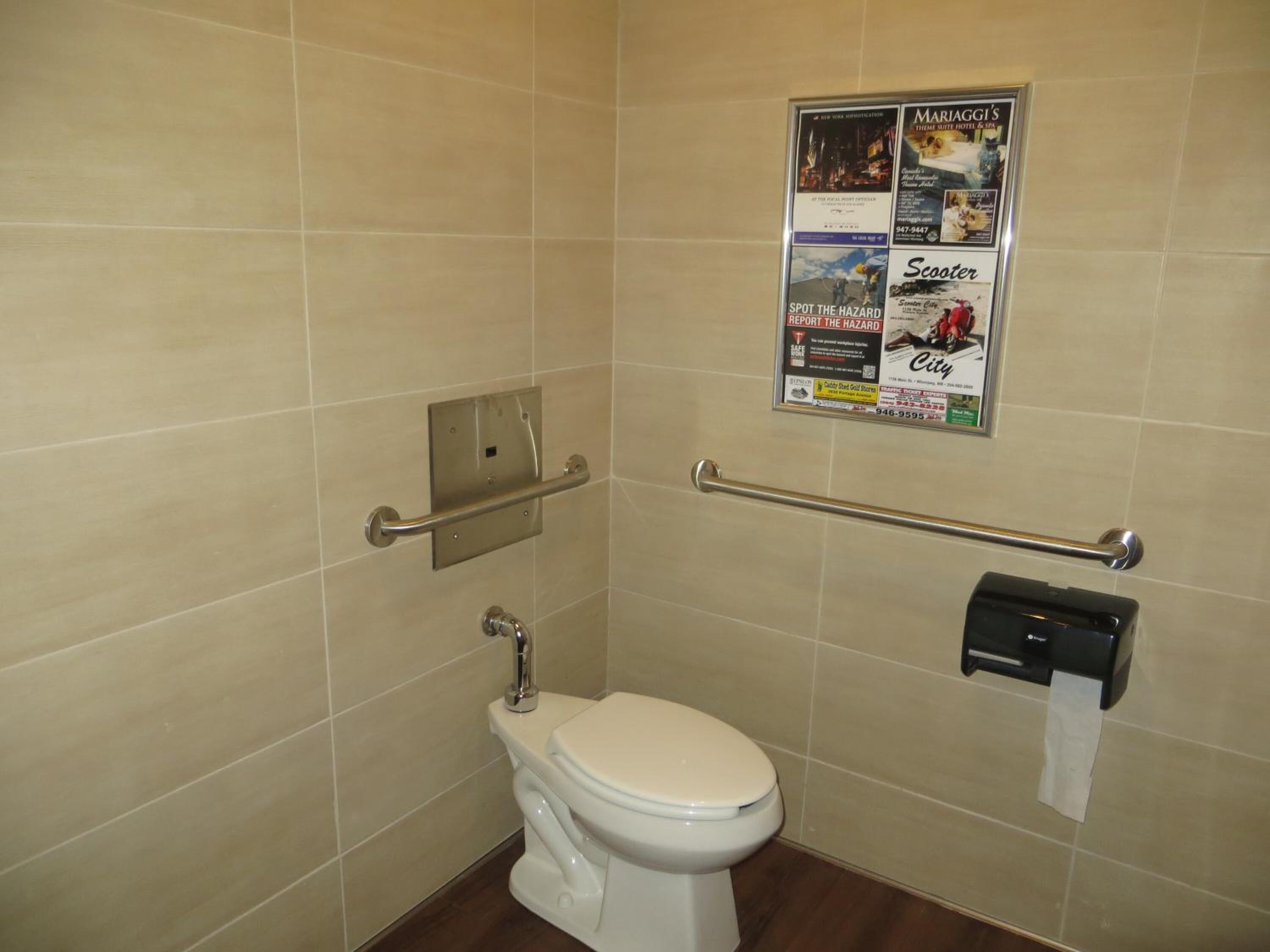 Ein kleines, privates Badezimmer mit Toilette, Haltegriff und Papierhandtuchhalter.
