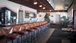 Zona de bar con mostrador, varios taburetes y una cocina al fondo.
