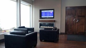 Una sala de estar moderna con un ventanal grande, un televisor de pantalla plana montado en la pared y una puerta de madera.