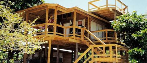 A wooden multi-level cabin with a staircase connecting the floors, surrounded by trees.
