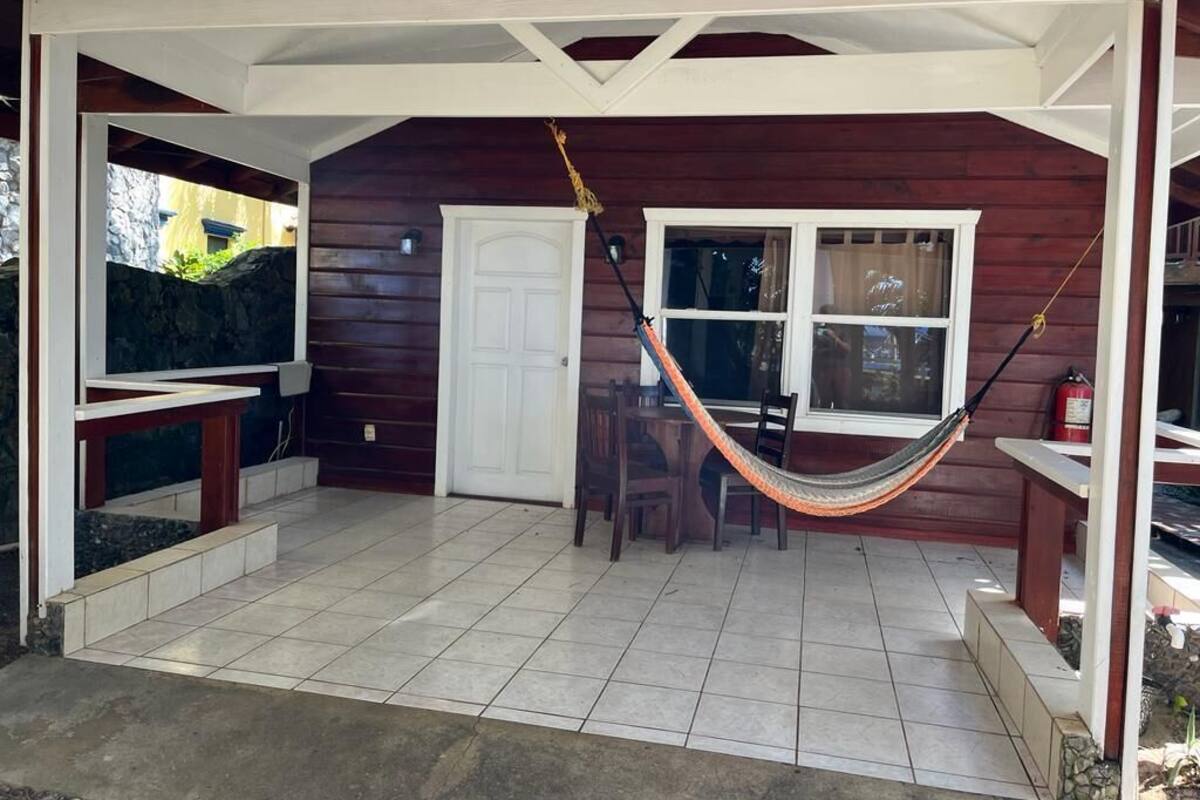 A covered patio with a hammock, a door, and a window.