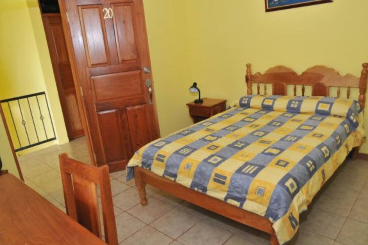 Ein Schlafzimmer mit einem hölzernen Bett, einem Nachttisch, einem Stuhl und einer Tür mit der Nummer 20.