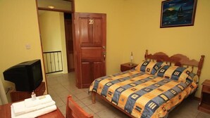 Een hotelkamer met een bed, een televisie, een houten deur en een schilderij aan de muur.
