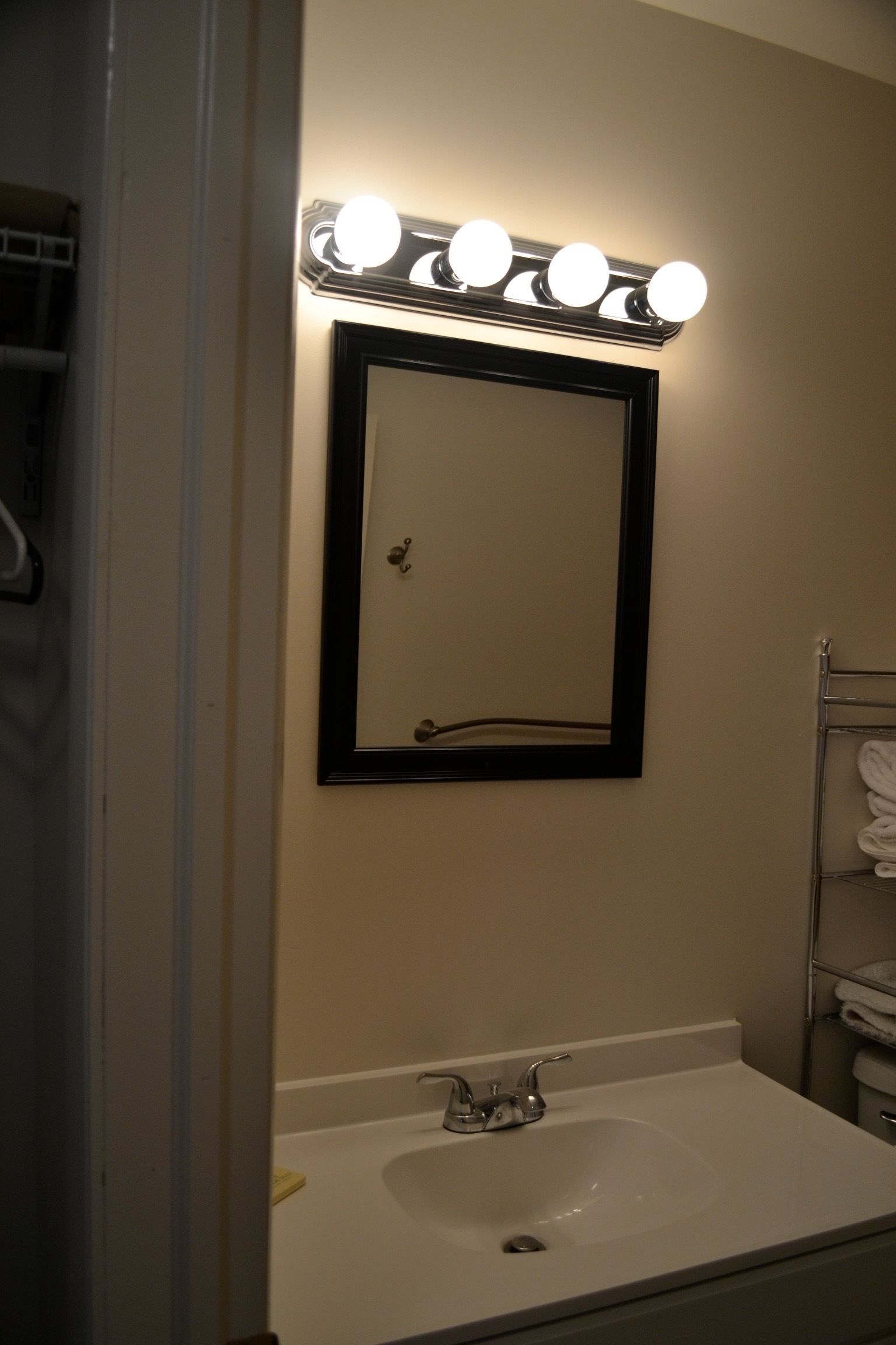 A bathroom with a sink, mirror, and towel rack.