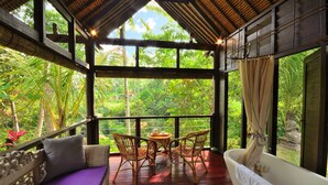 Une pièce avec un plancher en bois, une baignoire blanche, un canapé violet et une table avec des chaises.