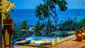A hot tub with a view of the ocean, surrounded by tropical plants and a wooden deck. - Private Villas of Bali (Kutuh)