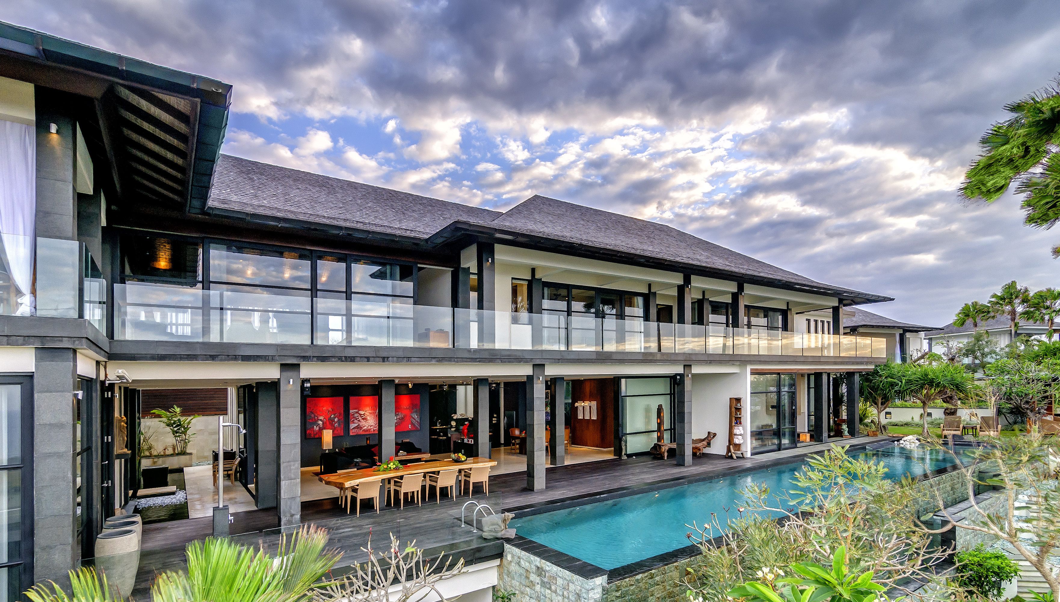 Une maison moderne à deux étages dotée d’un grand balcon, d’une piscine et d’un coin repas.