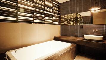 A modern bathroom with a bathtub, a sink, and a large mirror.