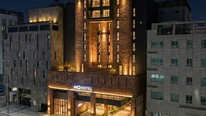 A hotel with a modern facade, multiple floors, and a well-lit entrance. - MD HOTEL DONGTAN (Hwaseong)