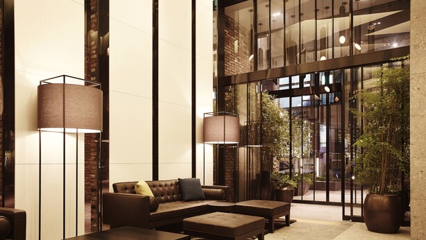 A spacious lobby with a sectional sofa, two armchairs, a coffee table, and a floor lamp. There are large windows and a potted plant in the corner. - MD HOTEL DONGTAN (Hwaseong)