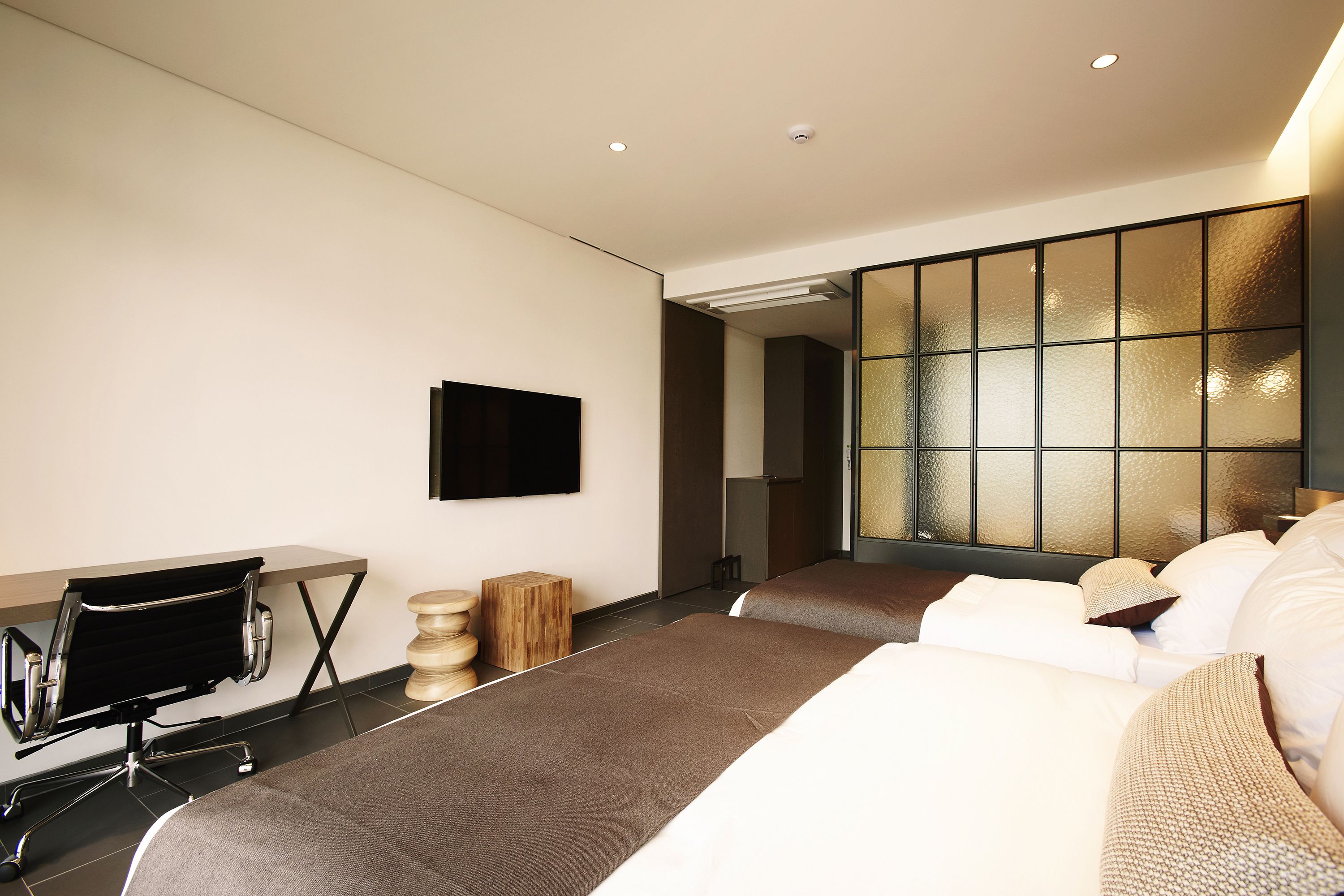 Una habitación de hotel moderna con una cama grande, un escritorio y un televisor en la pared.