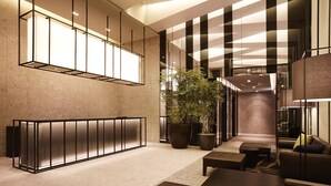 A modern lobby with a long reception desk, seating area, and large potted plants. - MD HOTEL DONGTAN (Hwaseong)