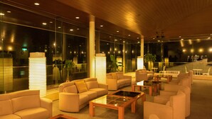 A modern lounge area with sofas, armchairs, and coffee tables, featuring large windows and a wooden ceiling. - Livemax Resort Itokawana (Ito)