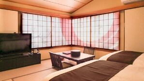 A traditional Japanese-style room with tatami flooring, a low table with a cushion, a television on a cabinet, and large shoji screens. - Livemax Resort Itokawana (Ito)