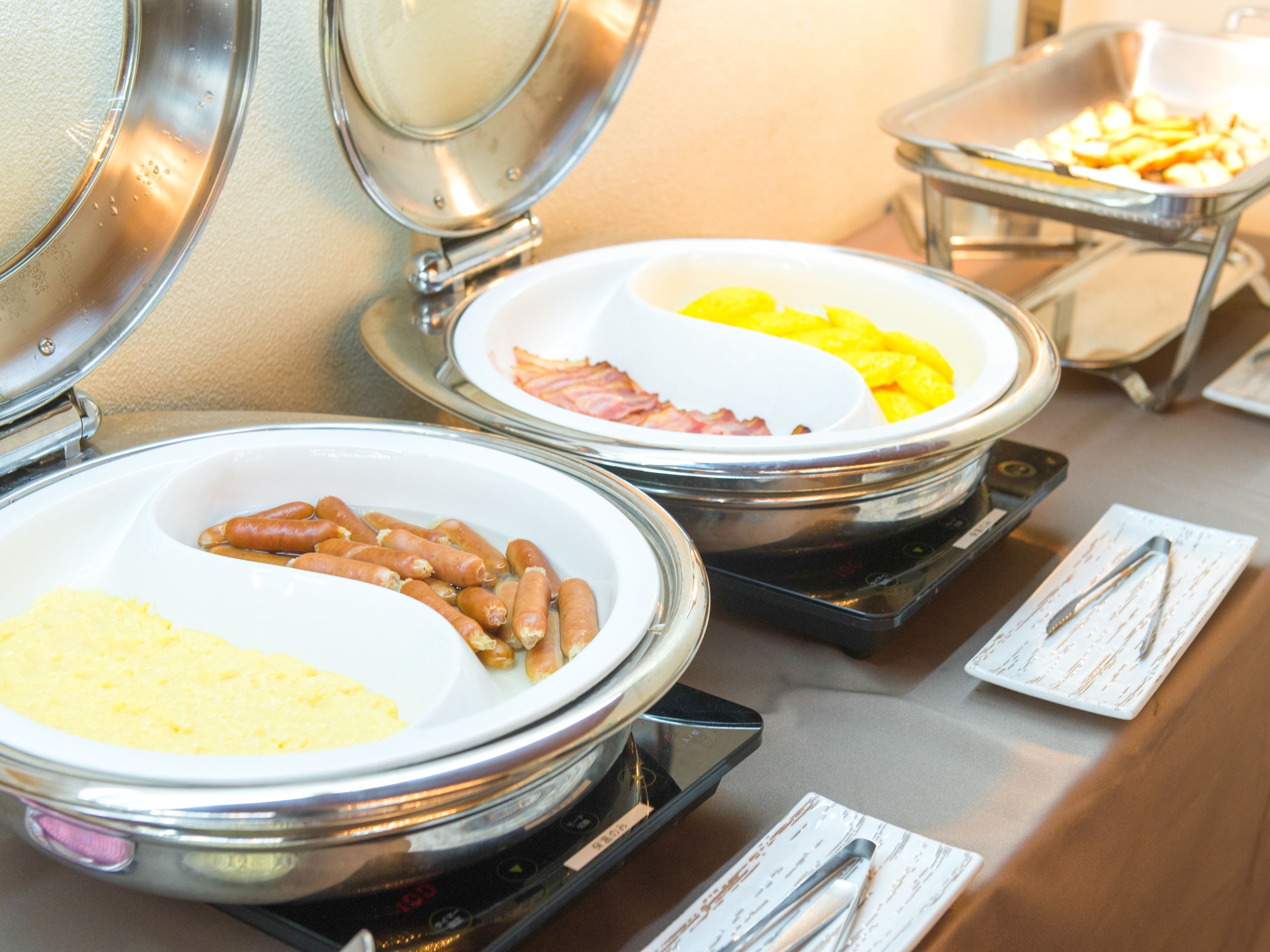 A buffet with various food items including sausages, eggs, and potatoes.