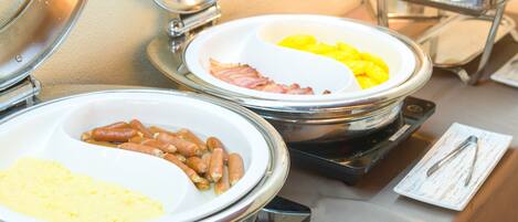 A buffet with various food items including sausages, eggs, and potatoes.