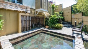 A swimming pool with stone tiles, a bamboo fence, and a chair. - Livemax Resort Itokawana (Ito)