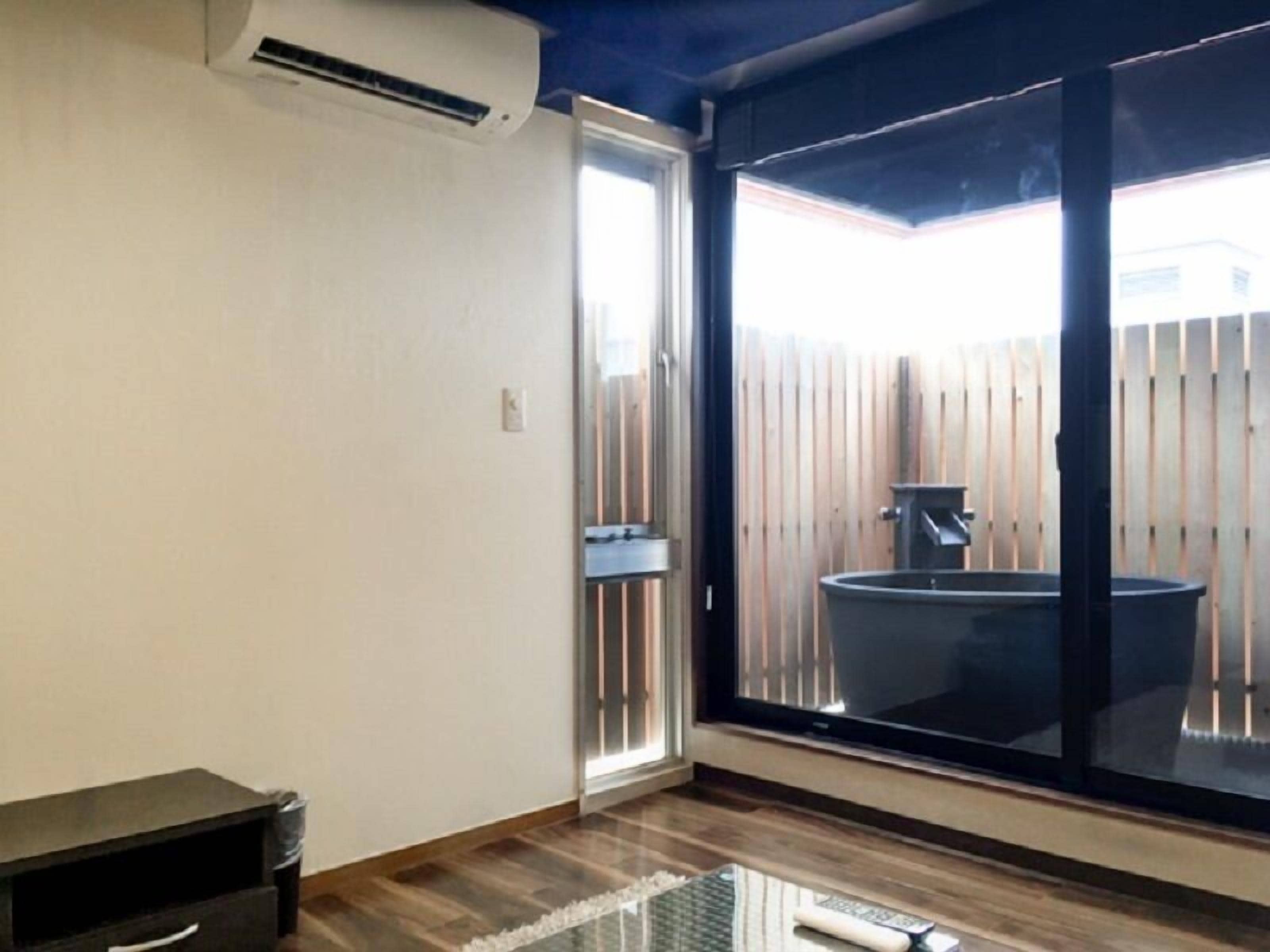 A room with a sliding glass door leading to a backyard, a small table, and a black cabinet.