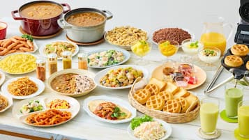Eine Auswahl an Speisen und Getränken auf einem Tisch, darunter Pasta, Suppe, Waffeln und Saft.
