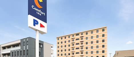 Un hotel Comfort Inn con un cartel de estacionamiento, edificios modernos y un cielo despejado.