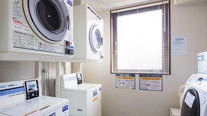 A laundry facility with multiple washing machines, a coin-operated washer, and instructional signs. - Comfort Inn Ogaki (Ogaki)