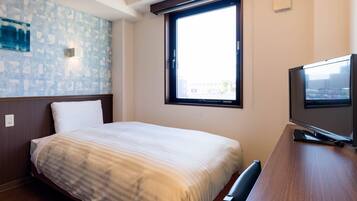 A hotel room with a bed, a television, a window with blinds, and a wall with a textured pattern.