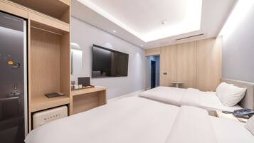 Una habitación de hotel moderna con una cama grande, un escritorio, un armario y un televisor montado en la pared.