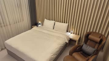 Una habitación de hotel con una cama grande, una mesita de noche con lámpara, un sillón de cuero marrón y una pared a rayas.