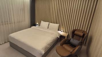 Una habitación de hotel moderna con una cama grande, una mesita de noche, una silla y una pared con listones verticales.