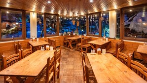 A restaurant with wooden tables and chairs, large windows with views of the outside, and a warm interior lighting. - Lodge Scole (Yamagata)