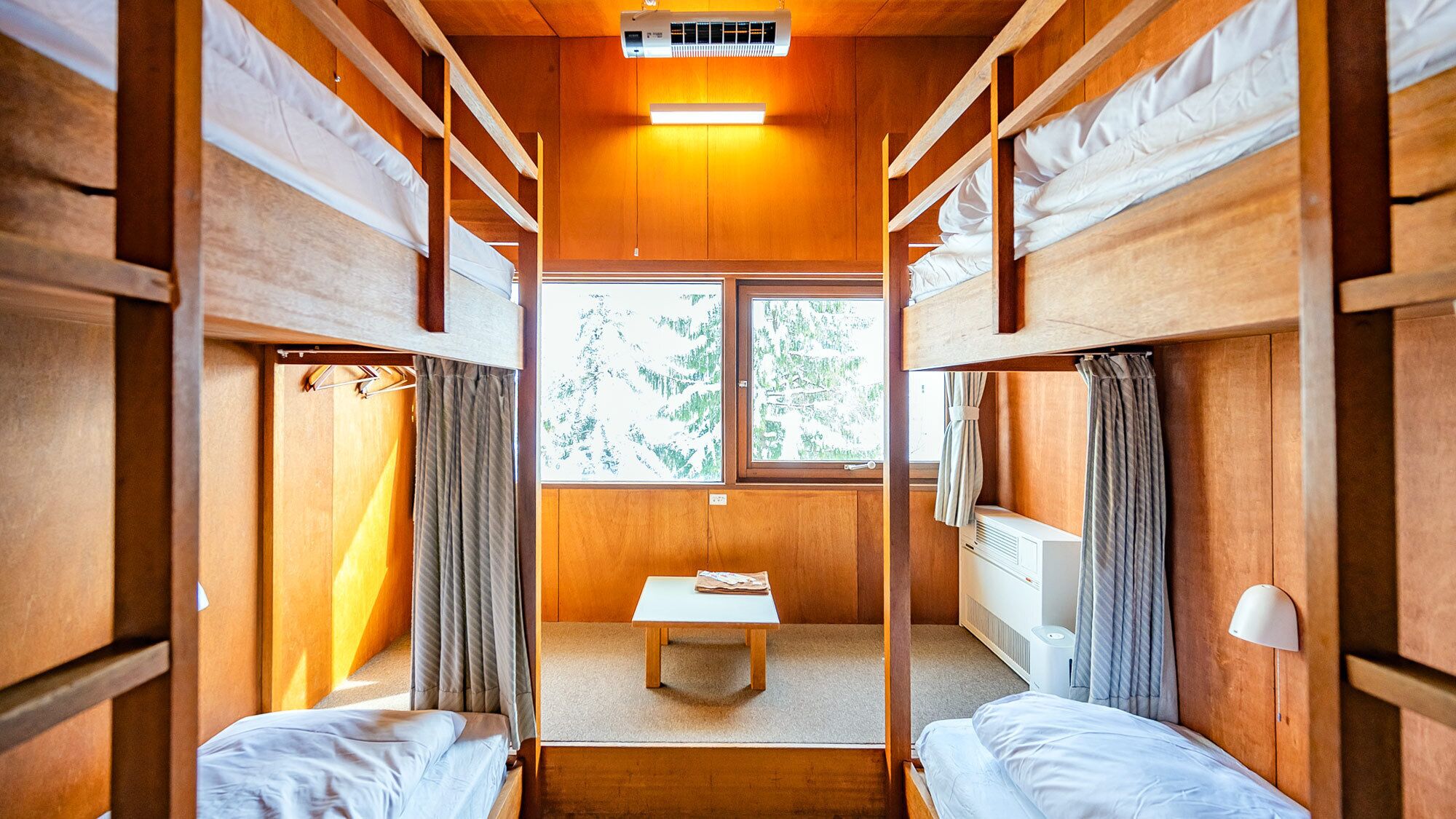 Una cabaña con literas, una mesita y una ventana con vistas a árboles.