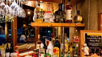 A bar area with various bottles of alcohol, a sign indicating happy hour, and a teddy bear decoration.