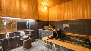 A traditional Japanese onsen with wooden walls, a wooden bathtub, and a separate shower area. - Lodge Scole (Yamagata)