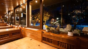 A restaurant with wooden furniture, large windows, and a view of the outside. - Lodge Scole (Yamagata)