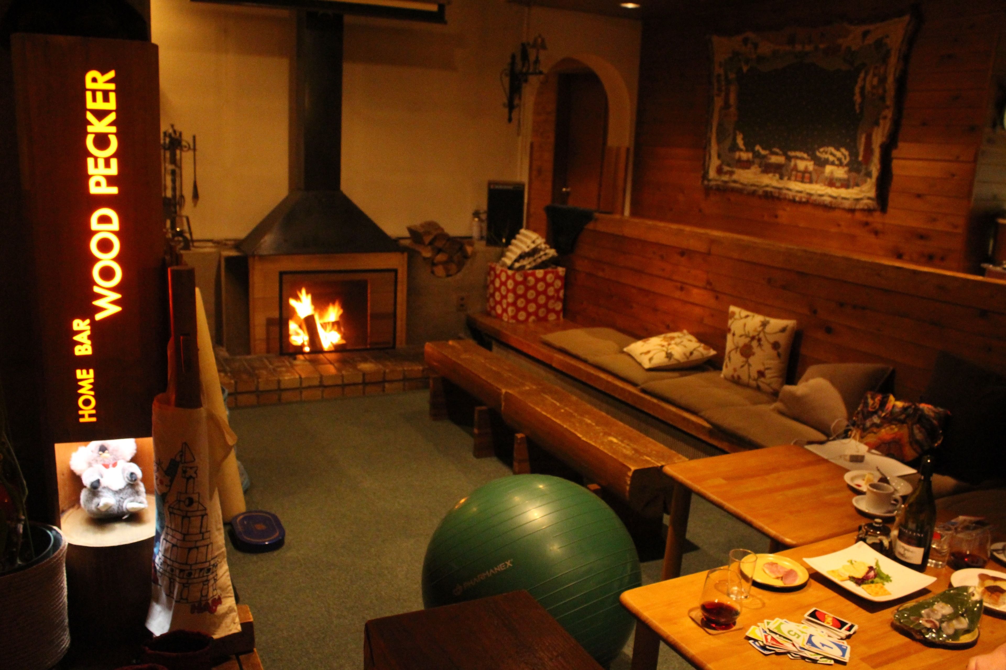 A cozy room with a fireplace, wooden furniture, a green exercise ball, and a table with food and drinks.