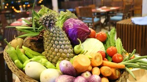 Una cesta con frutas y verduras sobre una mesa en un restaurante.
