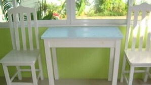 Um quarto pequeno com uma mesa branca e duas cadeiras brancas.