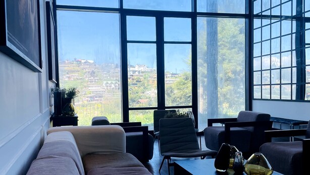 Una sala de estar moderna con un ventanal grande, un sofá, sillones y una mesa de centro.