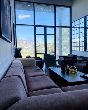 Een moderne woonkamer met een groot raam, een bank, stoelen en een salontafel.