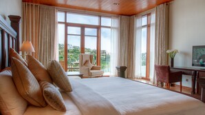 Un dormitorio amplio con una cama grande, un escritorio y una silla, con ventanas grandes y vistas al paisaje.