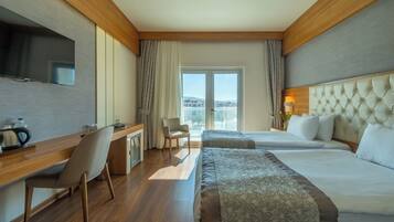 Habitación de hotel con dos camas, un escritorio, una silla, un televisor y vistas a la ciudad.