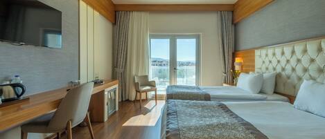 Habitación de hotel con dos camas, un escritorio, una silla, un televisor y vistas a la ciudad.