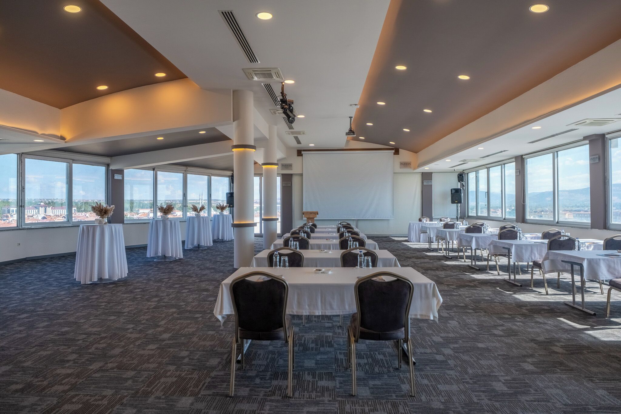 A conference room with tables and chairs, large windows, and a view of the city.