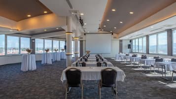 A conference room with tables and chairs, large windows, and a view of the city.