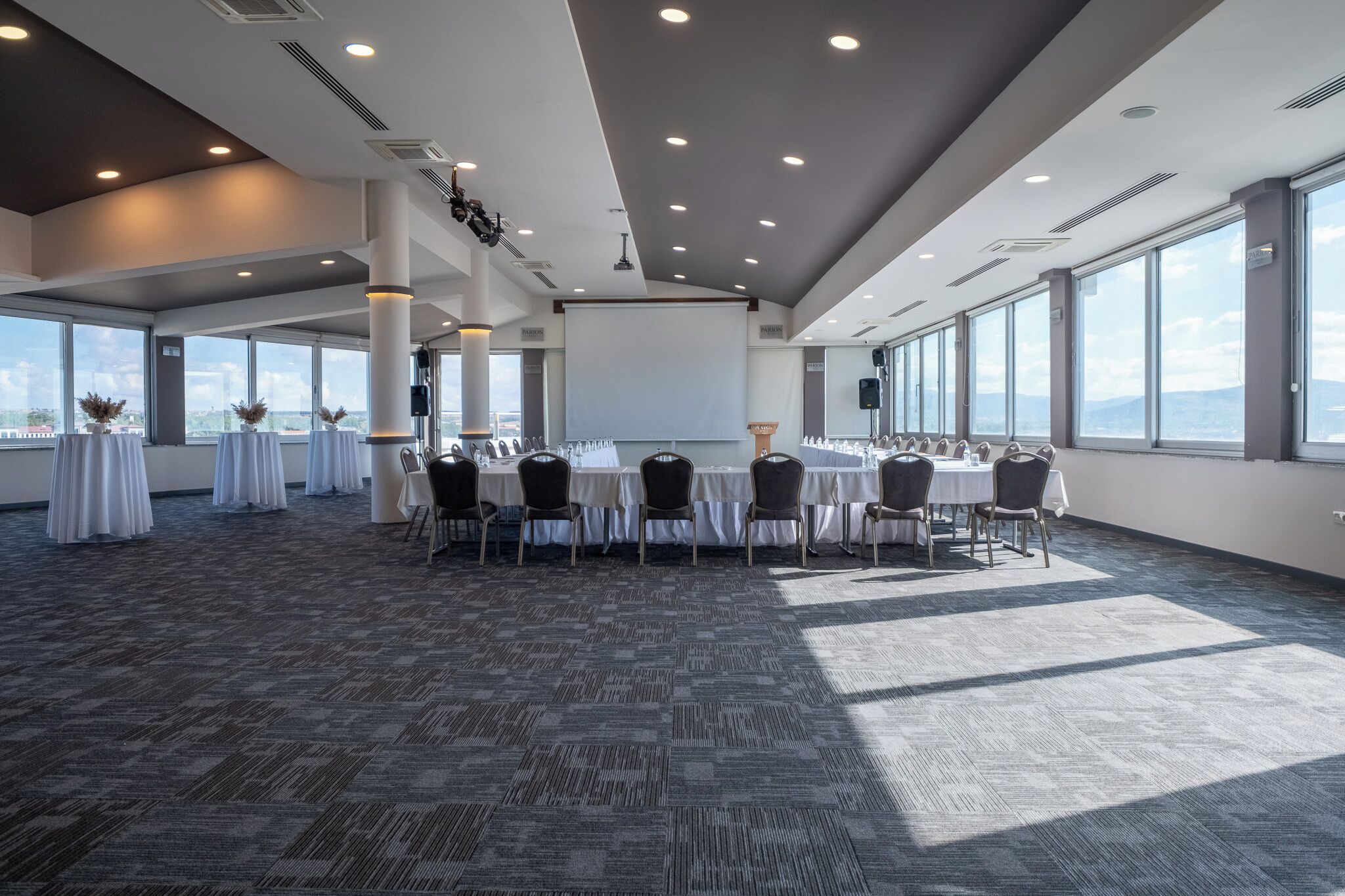 A conference room with a large table, chairs, and a projector screen.