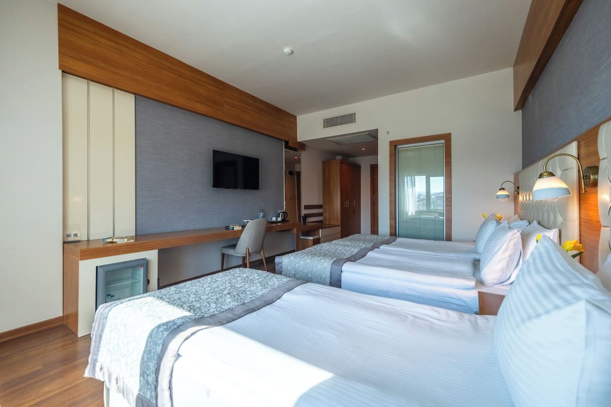 A hotel room with two beds, a desk, a TV, and a minibar.
