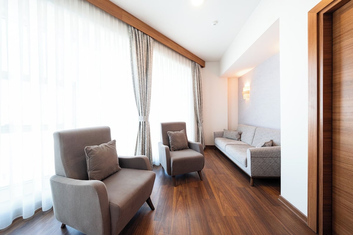 A modern living room with a wooden floor, two sofas, and a chair.